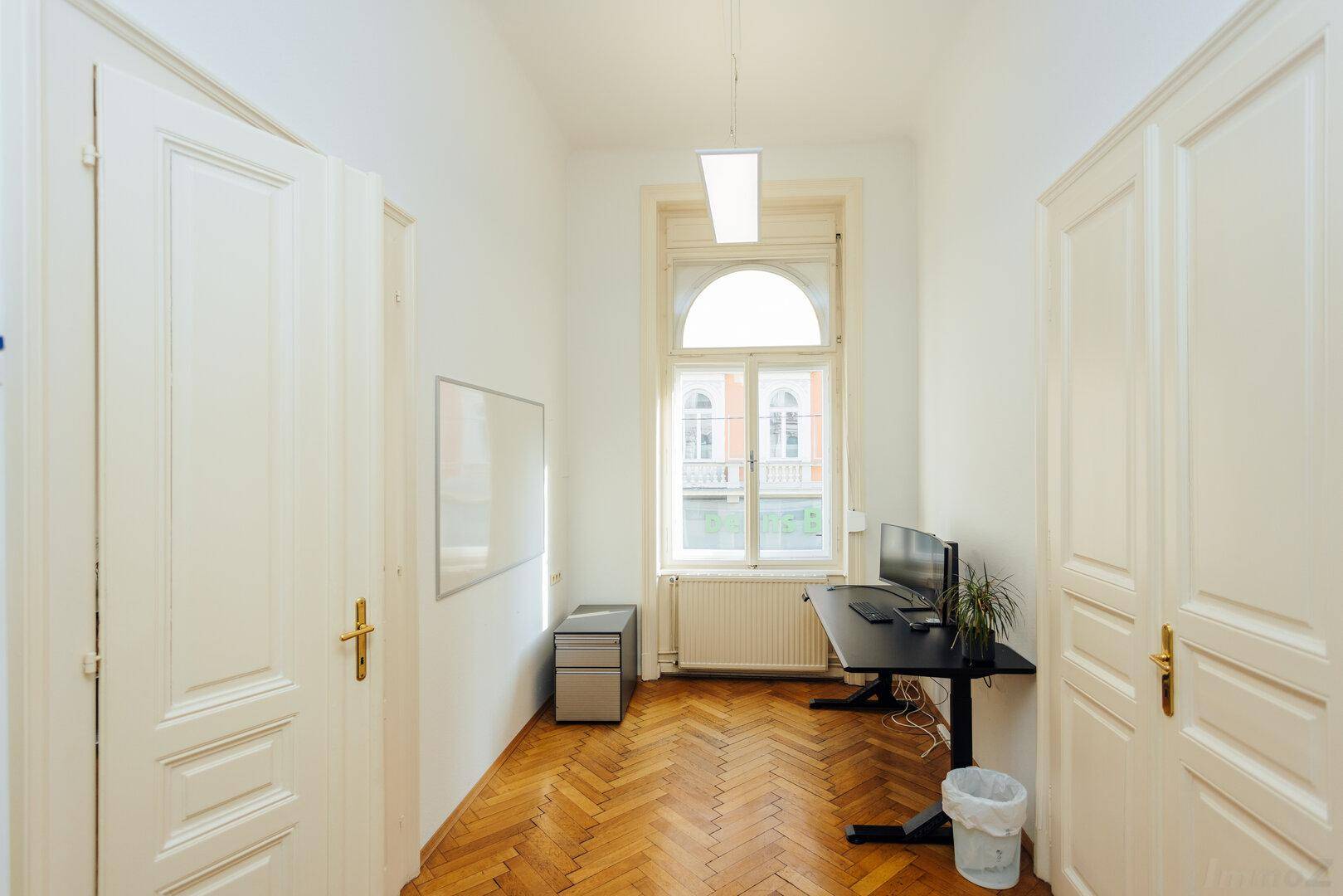 Ruhiges Einzelbüro mit Schreibtisch, Whiteboard und einem großen Fenster für viel Tageslicht.