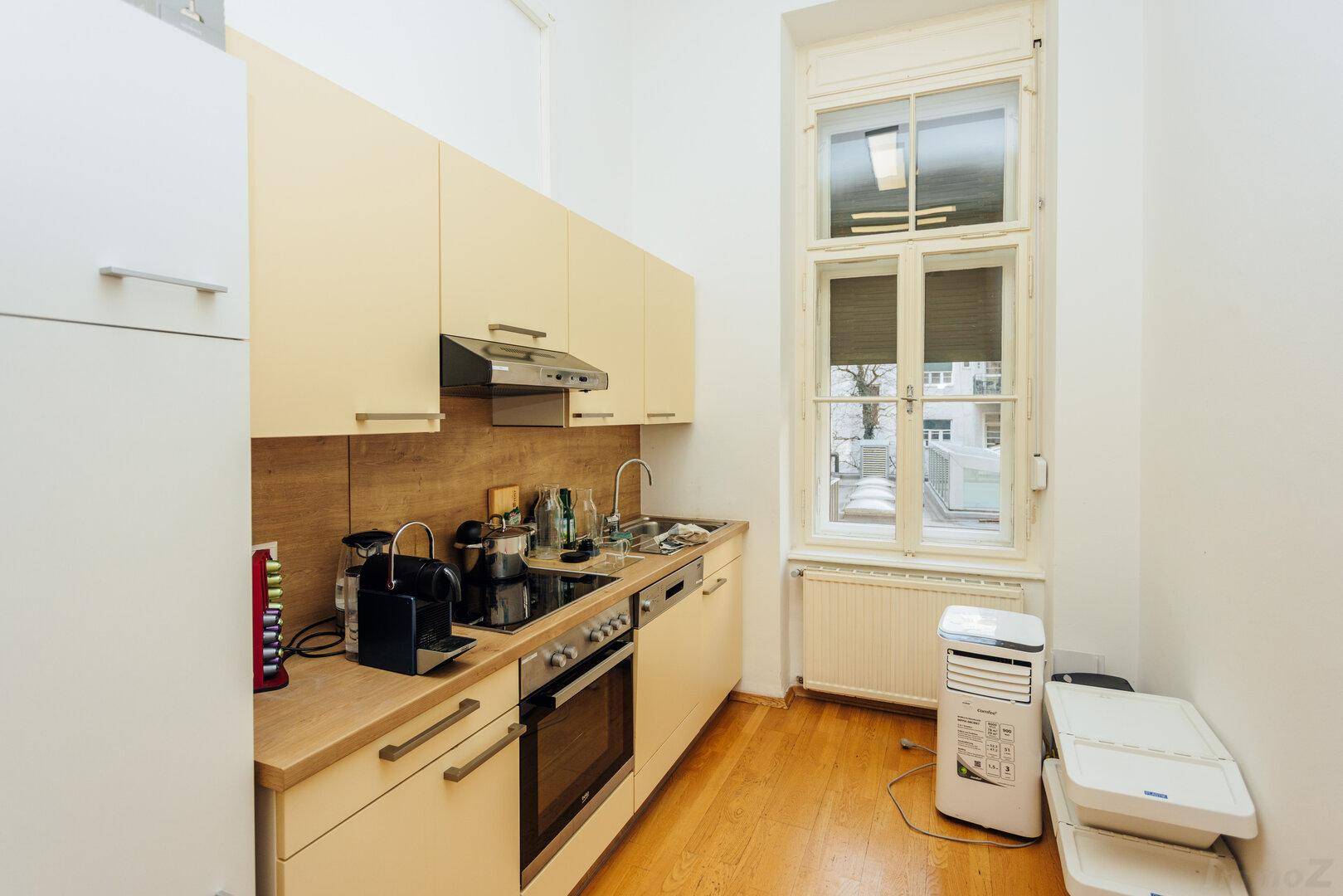 Funktionale Küchenzeile mit hellen Schränken, Holzarbeitsplatte und einem Fenster.