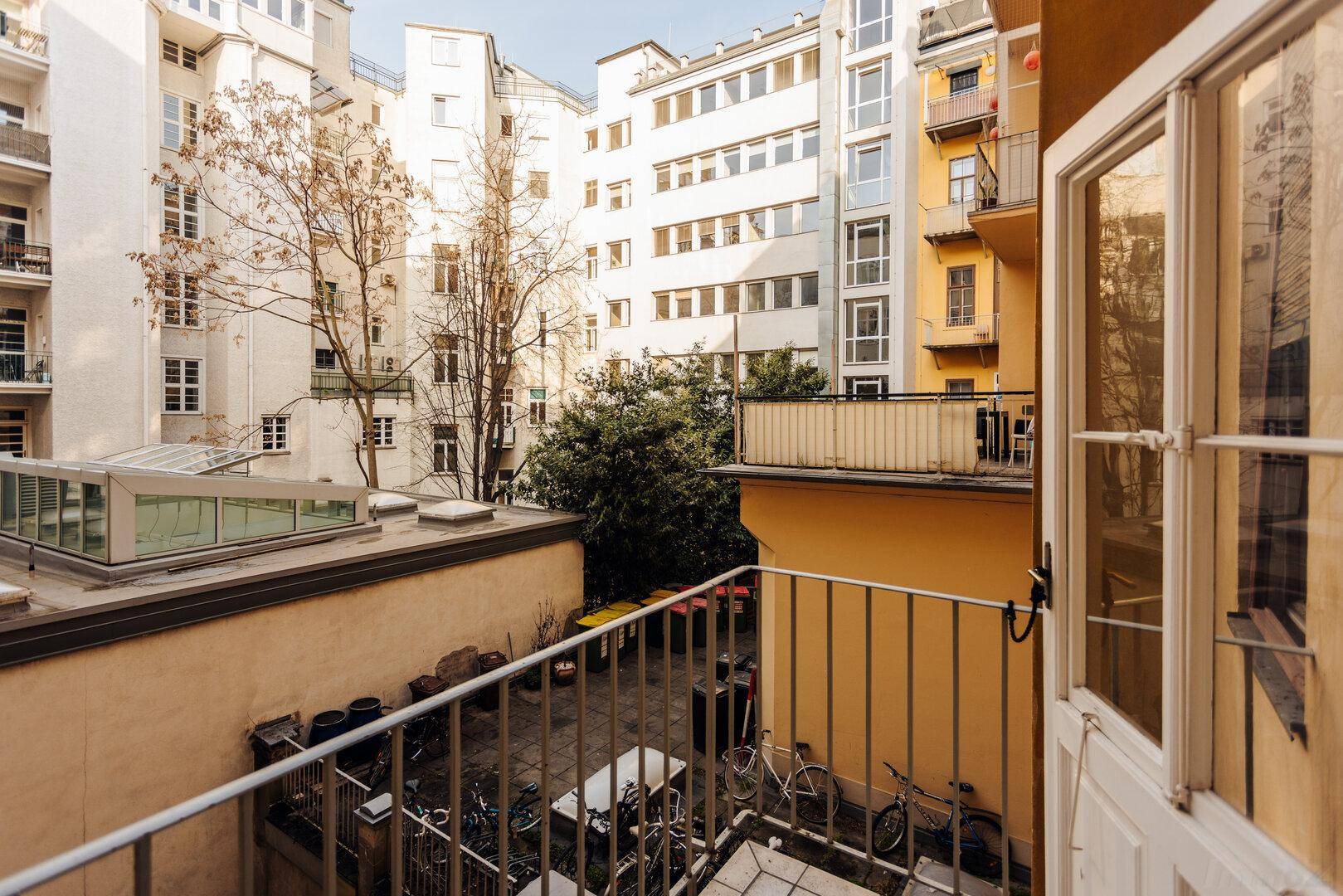 Balkon mit Blick auf einen ruhigen Innenhof und umliegende Gebäude.