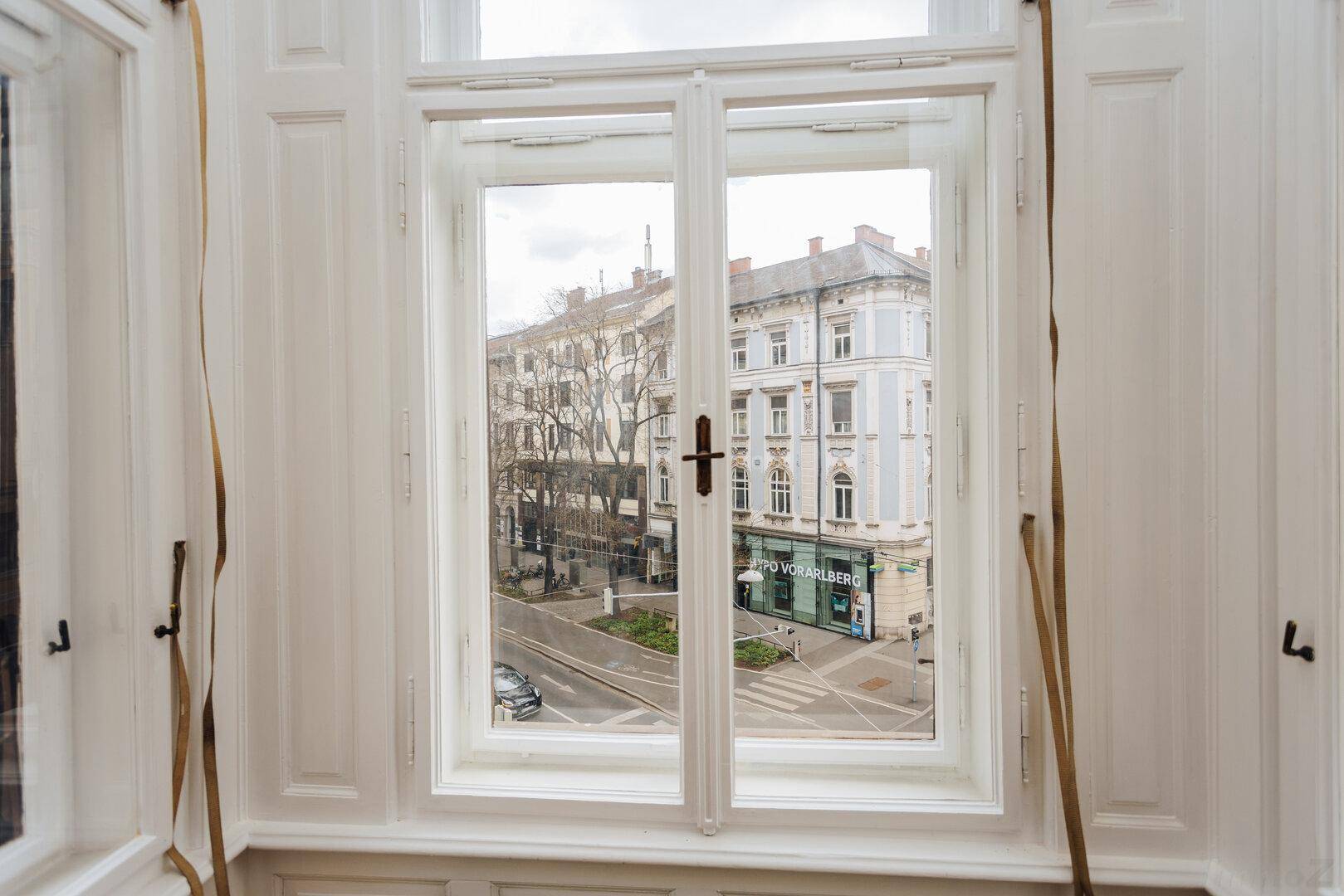 Detailansicht eines hohen Fensters mit Blick auf die gegenüberliegende historische Architektur.