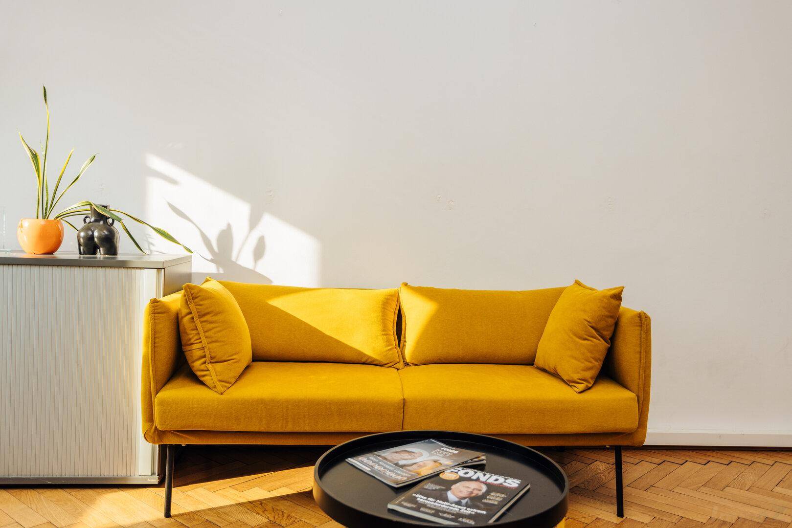 Gemütliche Sitzecke mit gelbem Sofa, Beistelltisch und natürlichem Lichteinfall.