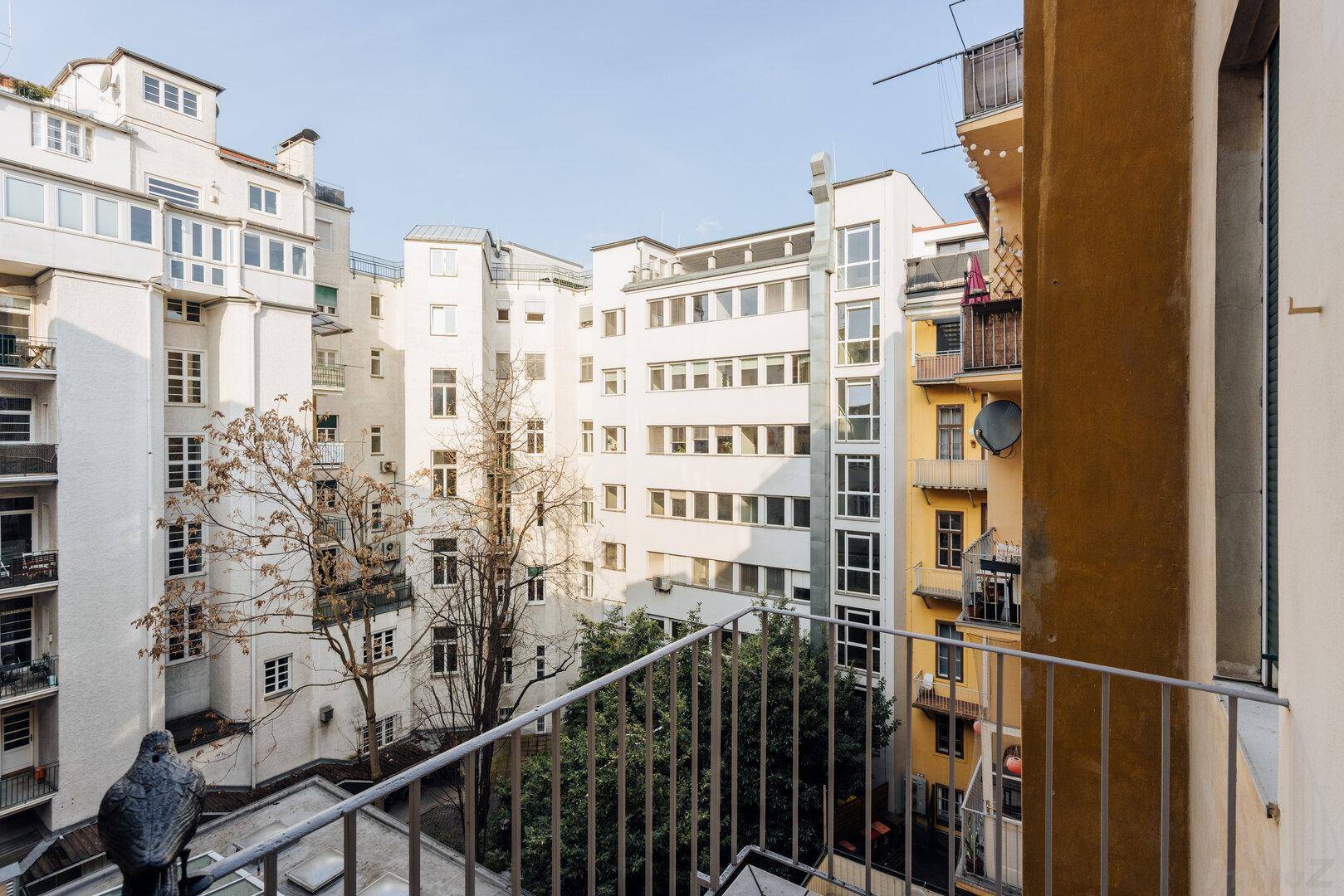 Balkon mit Blick auf den Innenhof und umliegende Gebäude.
