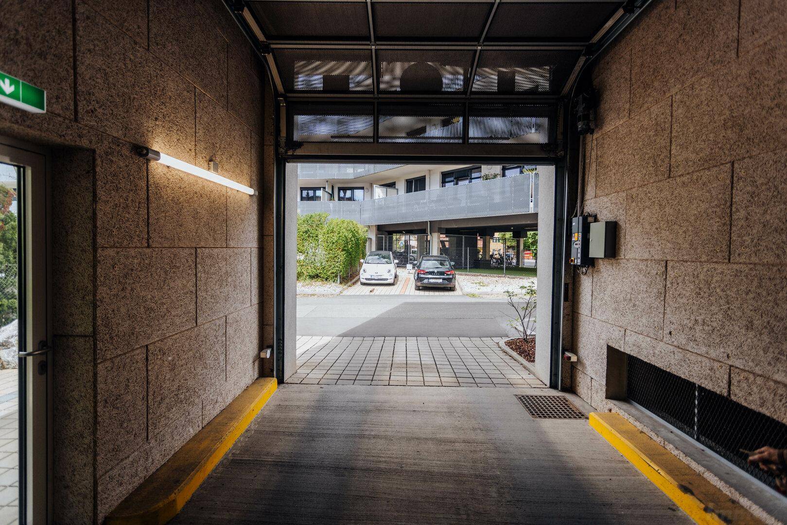 Einfahrt zur Tiefgarage mit Blick auf den Außenbereich und weitere Parkplätze.