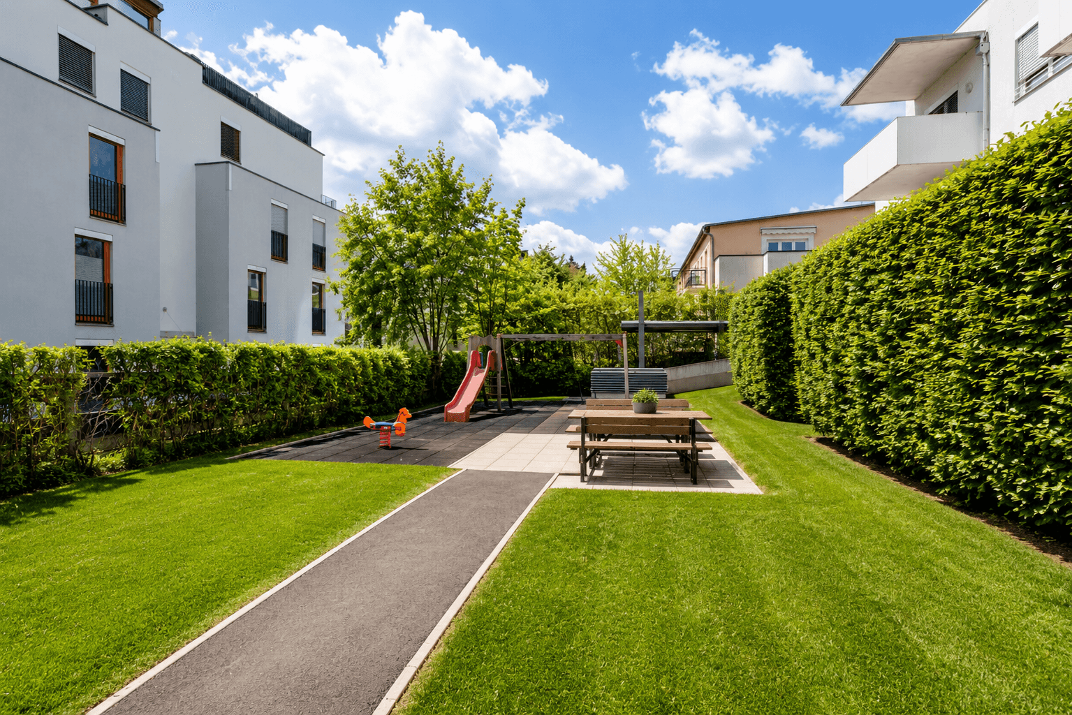 Gepflegter Gemeinschaftsgarten mit Spielplatz, Rasenfläche und Hecken.