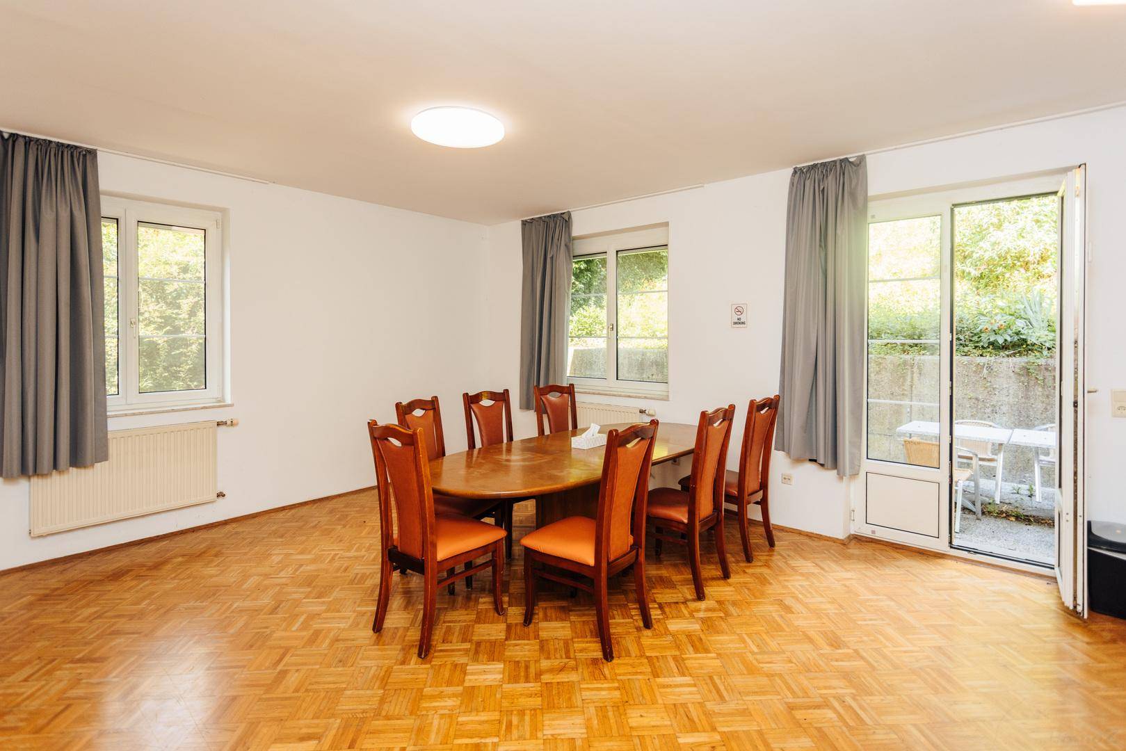 Heller Essbereich mit Holztisch, Stühlen und Zugang zu einer Außenterrasse.