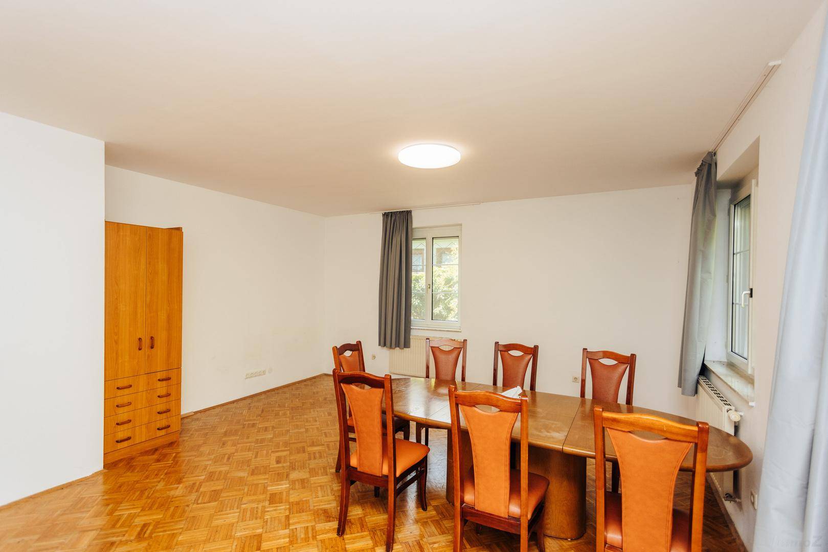 Geräumiger Essbereich mit Holztisch, Stühlen und einem großen Holzschrank.