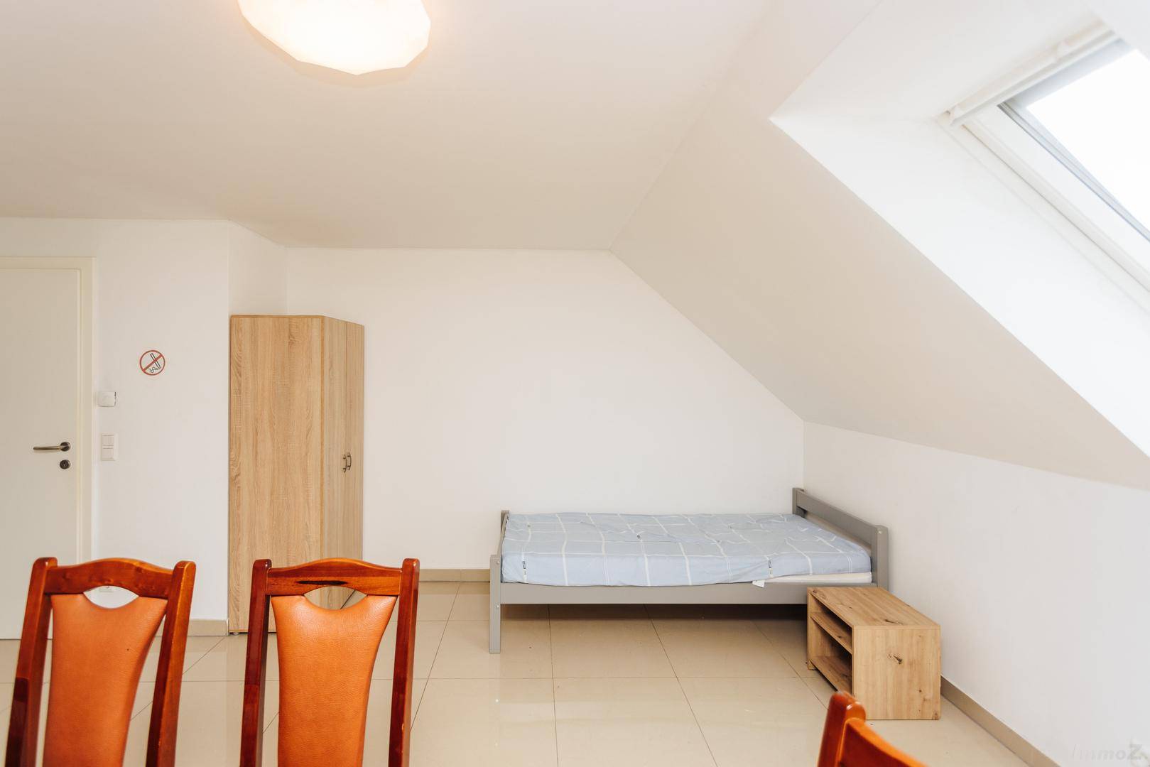 Dachgeschosszimmer mit Einzelbett, Schrank und Dachfenster.