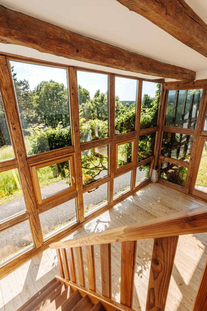 Lichtdurchfluteter Bereich mit Holztreppe und Panoramafenstern, die einen weiten Blick in die Natur bieten.