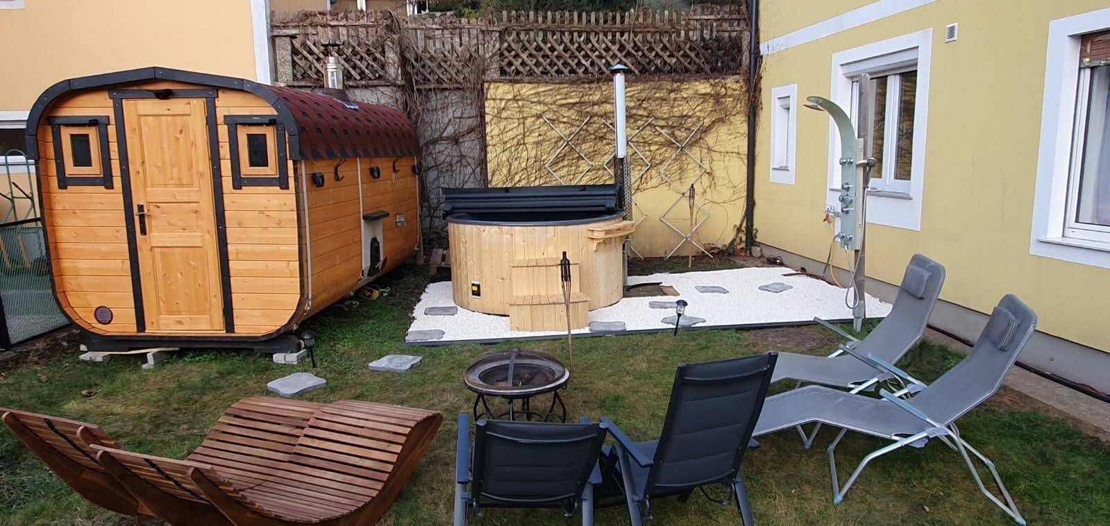Entspannender Gartenbereich mit Fasssauna, Hot Tub und Liegestühlen für Wellness im Freien.