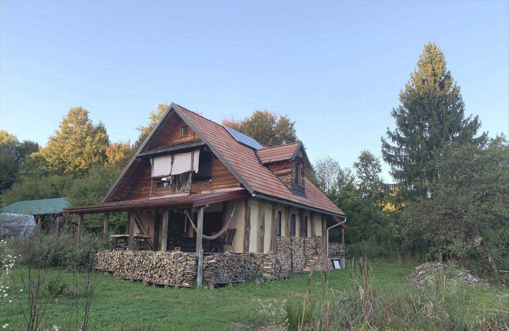 Gemütliches Landhaus mit Holzelementen, Ziegeldach und Solaranlage in grüner Umgebung.
