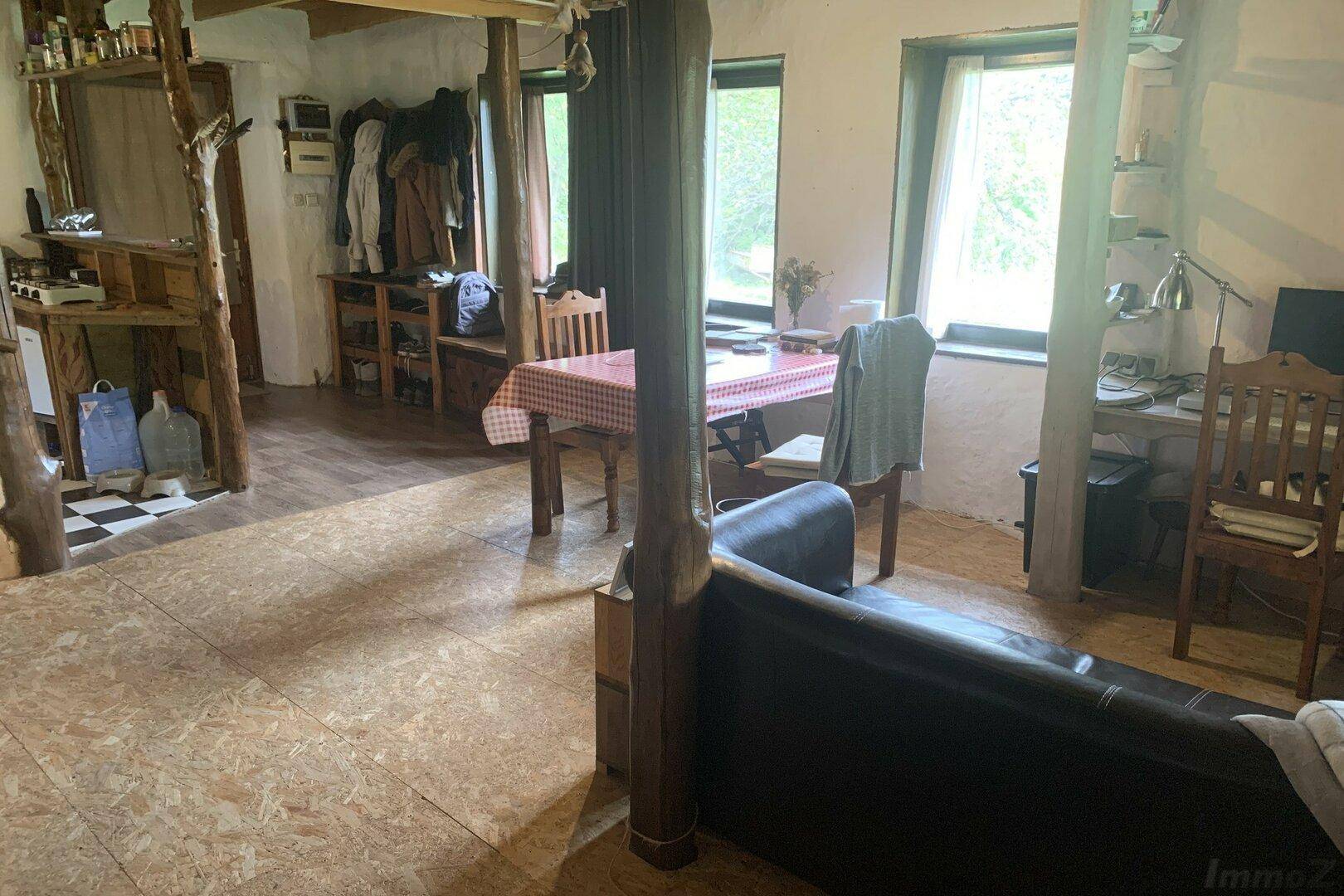 Rustikaler Wohn- und Essbereich mit Holzbalken, kariertem Tisch und Ledersofa.