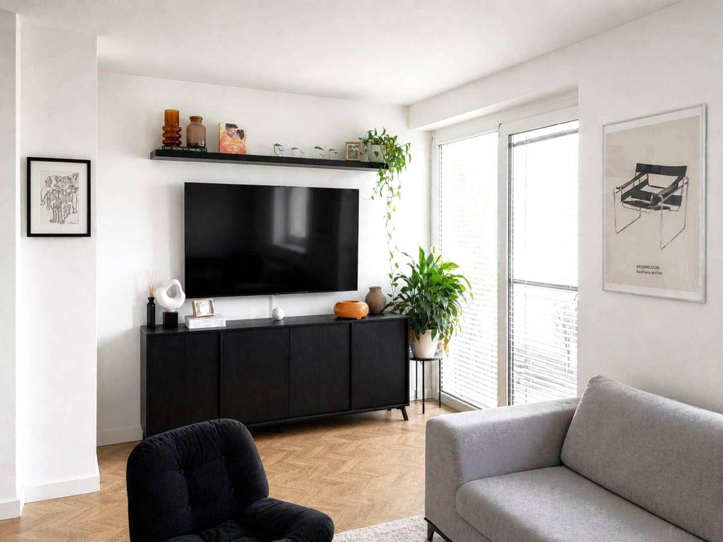 Helles Wohnzimmer mit modernem TV-Möbel, Pflanzen und Zugang zum Balkon.