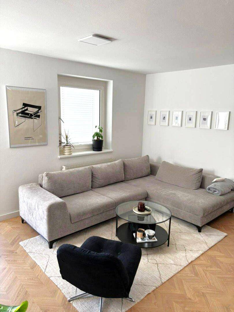 Gemütliches Wohnzimmer mit großem Ecksofa, Couchtisch und hellem Parkettboden.
