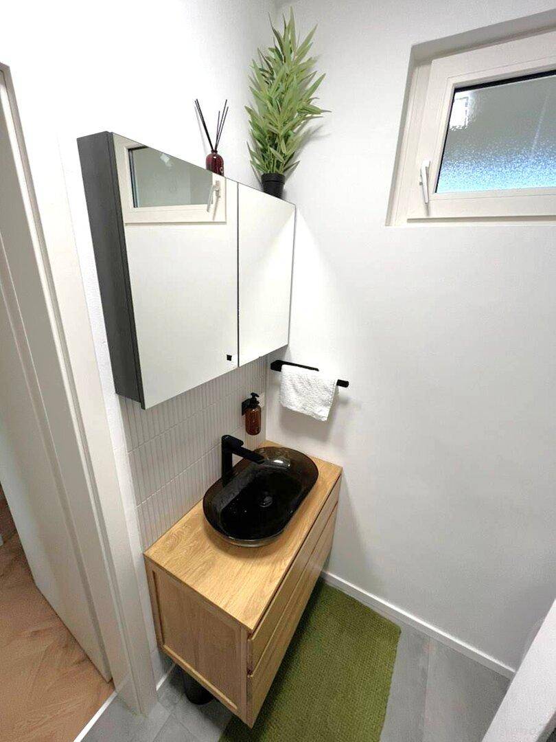 Modernes Badezimmer mit Holzwaschtisch, Aufsatzwaschbecken und Spiegelschrank.