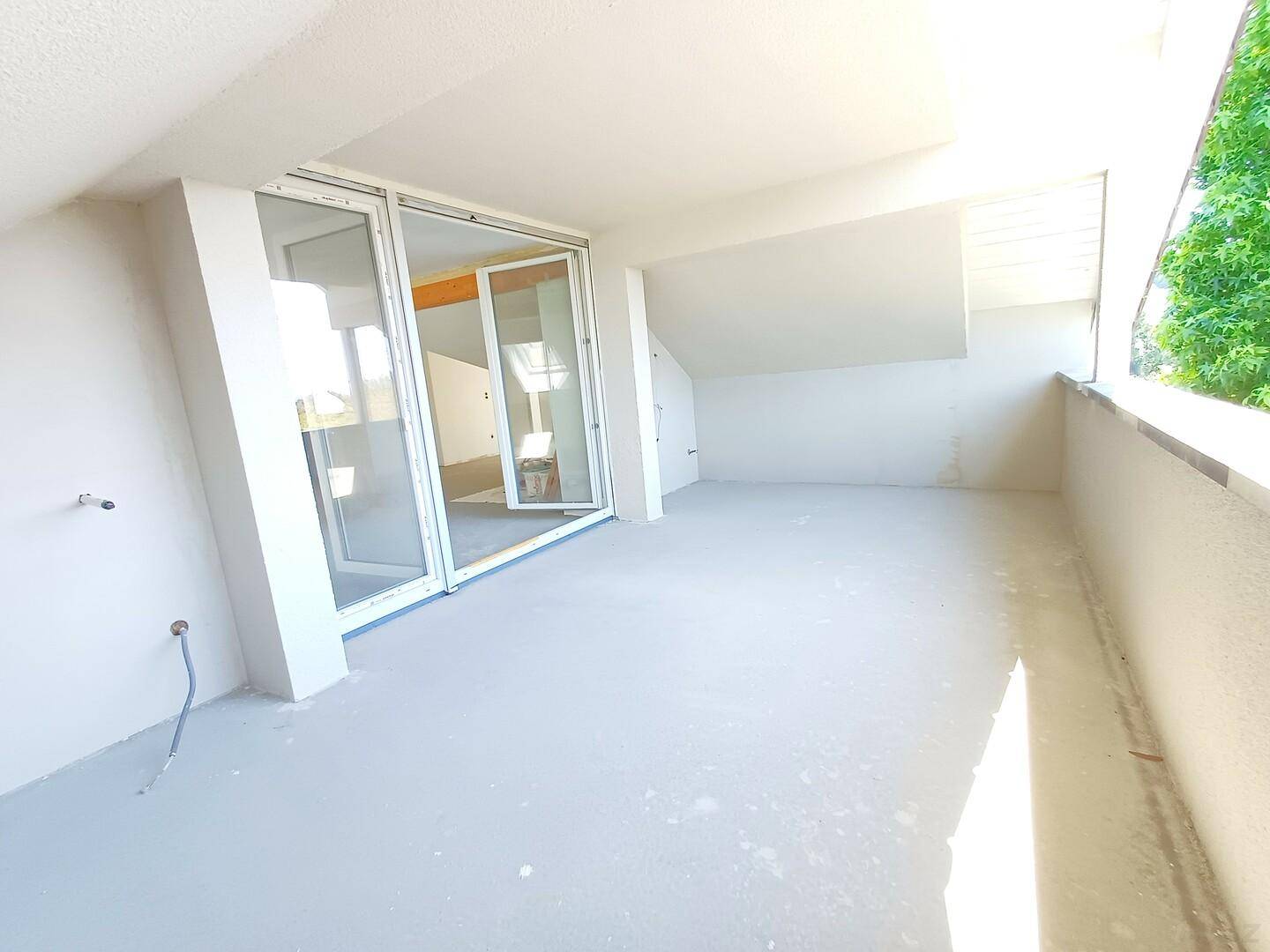 Unfertiger Balkonbereich mit großen Schiebetüren, bereit für den Ausbau und viel Tageslicht.