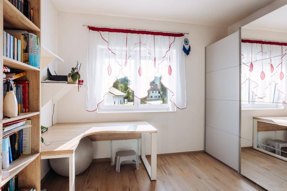 Helles Arbeitszimmer mit Holzschreibtisch, Bücherregal und Blick auf die umliegenden Häuser.