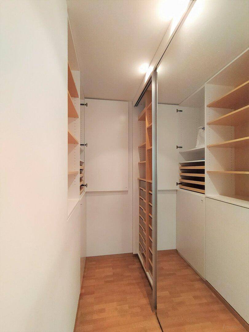 Geräumiger begehbarer Kleiderschrank mit vielen Ablagemöglichkeiten und Spiegel.