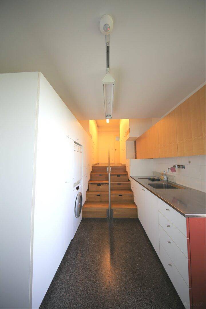 Praktischer Hauswirtschaftsraum mit Waschmaschine, Spüle und Zugang zur Treppe.