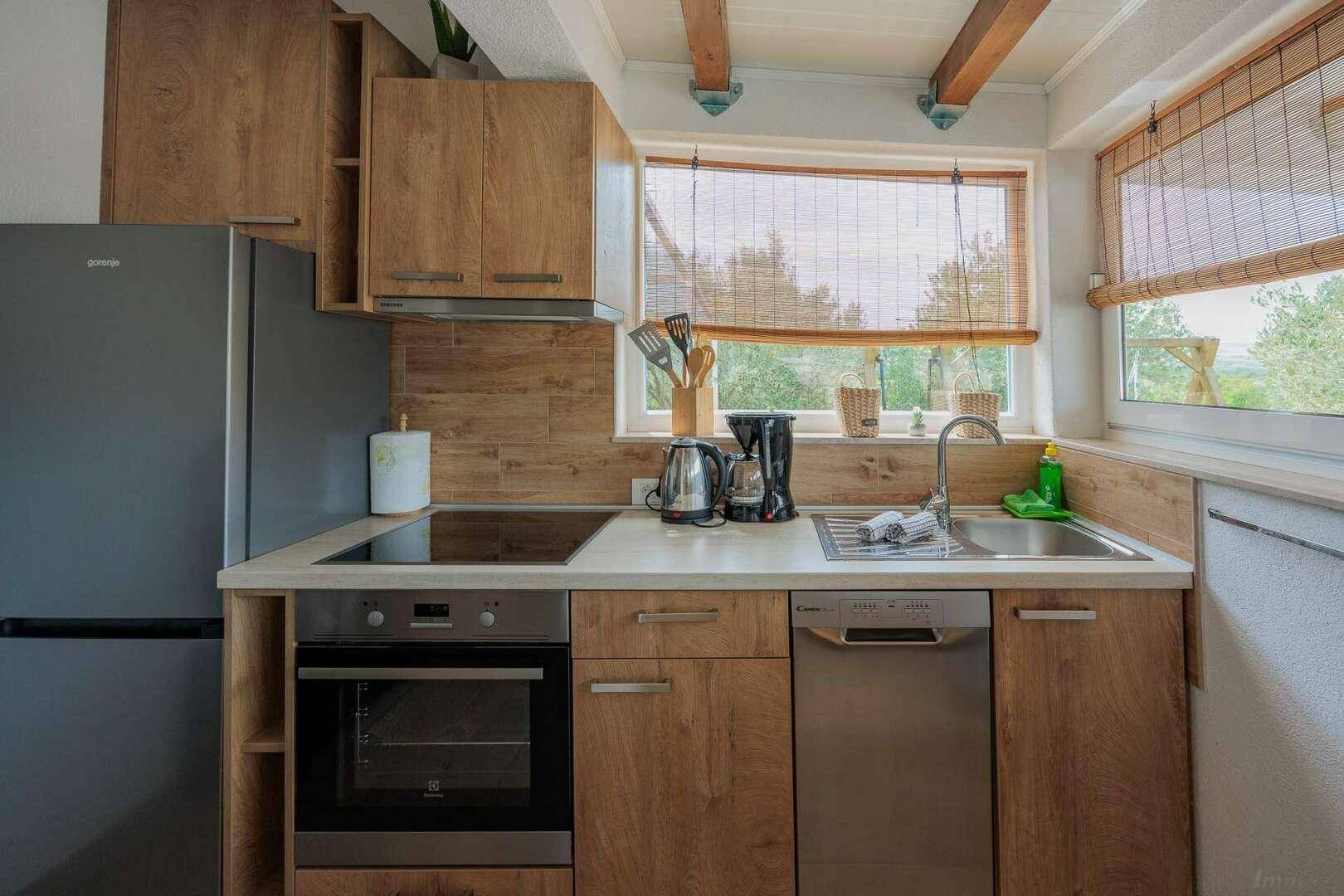 Funktionale Küche mit Holzfronten, Spüle, Kochfeld und integriertem Geschirrspüler.