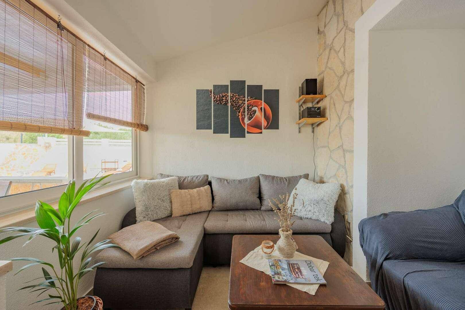 Helles Wohnzimmer mit bequemer Eckcouch, modernen Bildern und dekorativen Pflanzen.