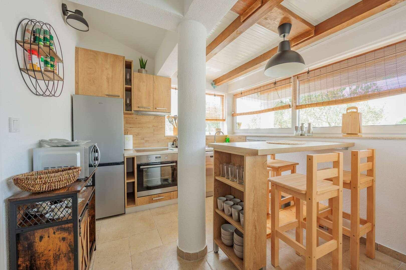 Gemütliche Küche mit Holzschränken, integrierten Geräten und einem kleinen Essbereich mit Barhockern.