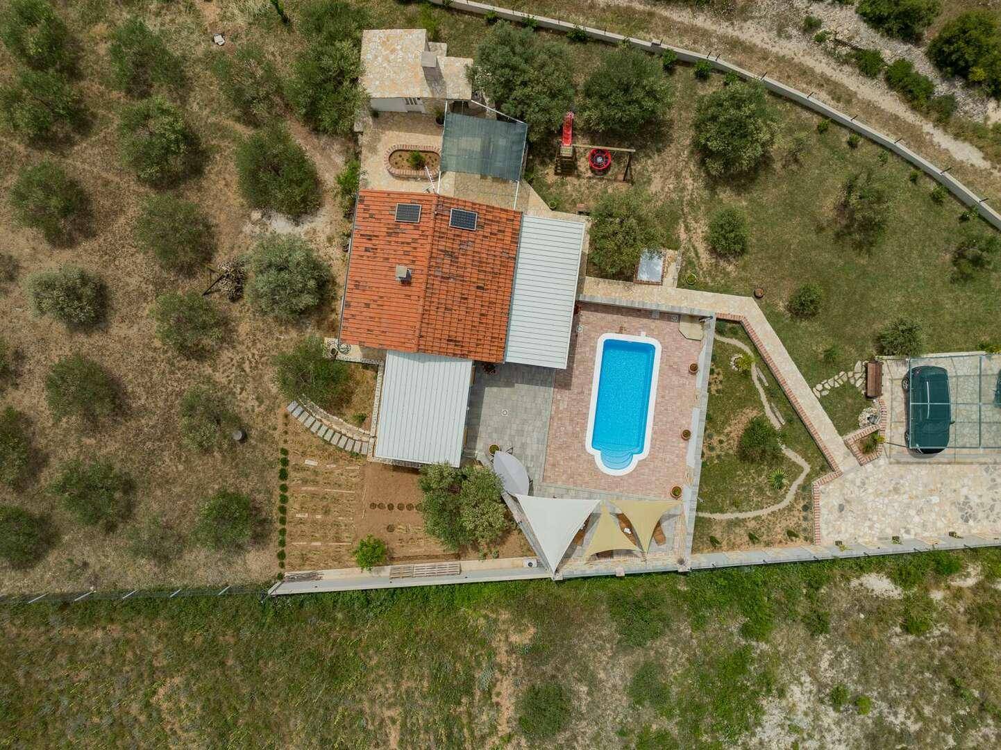 Draufsicht auf das Anwesen mit rotem Ziegeldach, Pool und gepflegtem Gartenbereich.