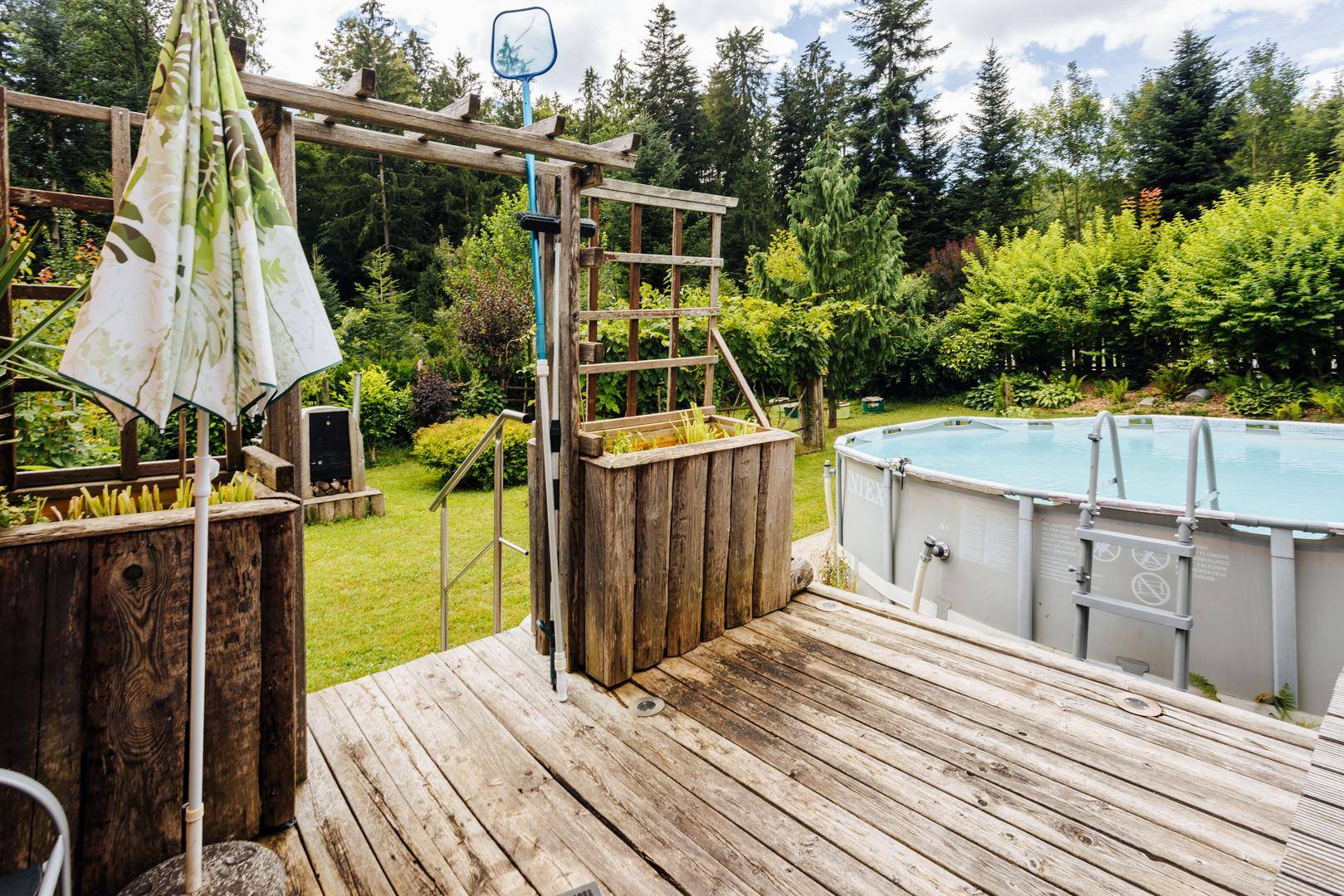 Holzterrasse neben dem Aufstellpool, ideal für Entspannung im Freien.