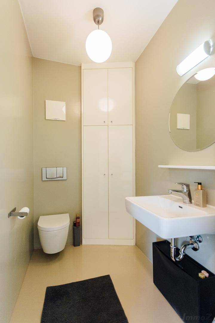 Helles Gäste-WC mit wandhängendem WC, modernem Waschbecken und Einbauschrank.