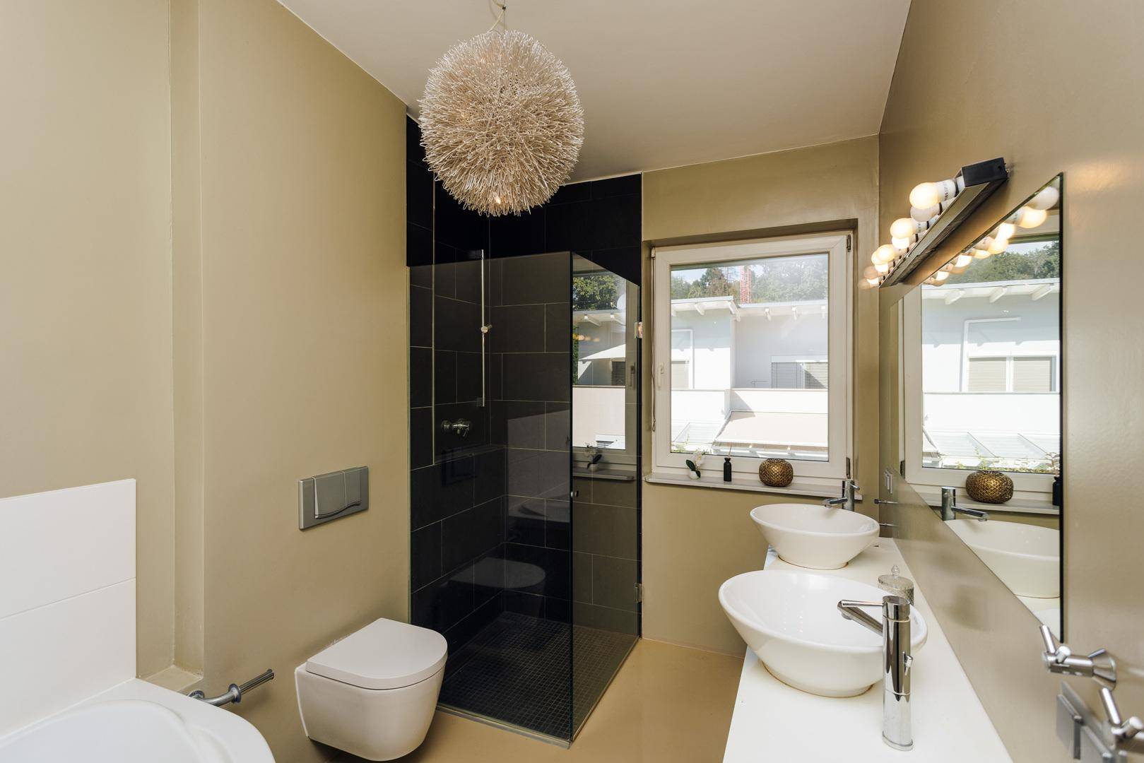 Modernes Badezimmer mit Doppelwaschbecken, Dusche, WC und Fenster für Tageslicht.
