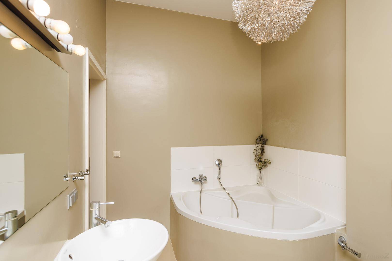 Geräumiges Badezimmer mit Eckbadewanne, modernem Waschbecken und großem Spiegel.