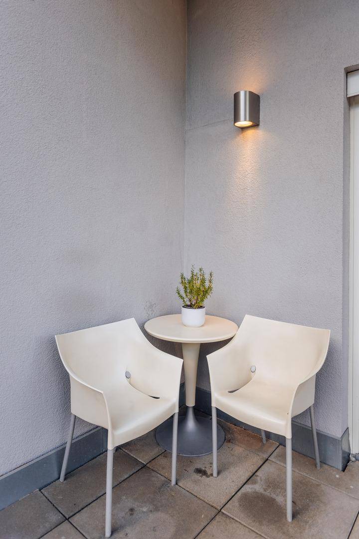 Gemütliche Sitzecke auf der Terrasse mit zwei Stühlen und einem kleinen Beistelltisch.