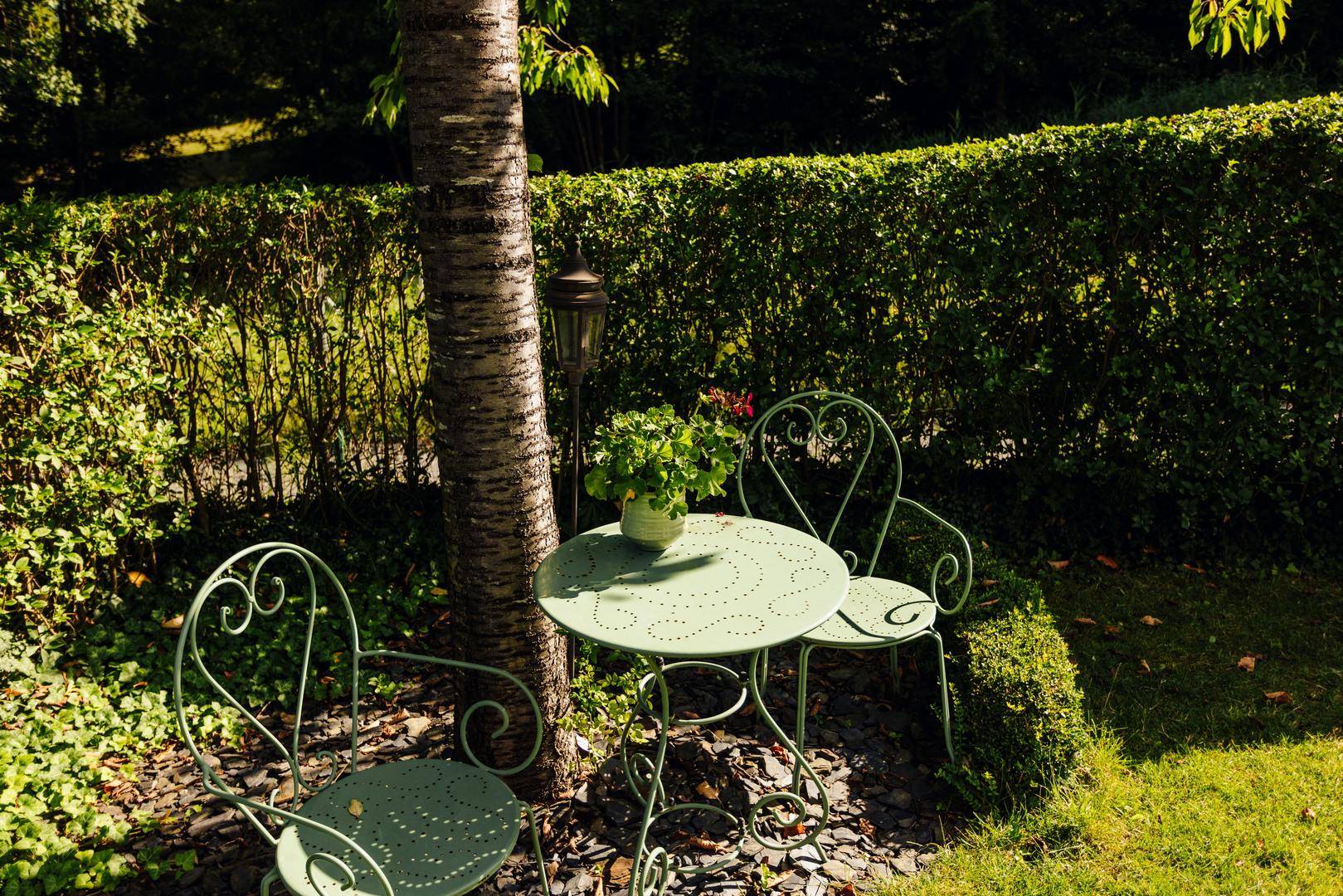 Gemütliche Sitzecke im Garten unter einem Baum, ideal für entspannte Stunden im Freien.