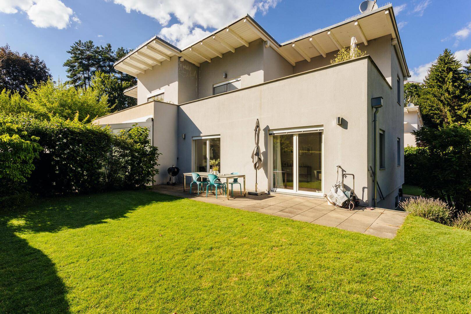 Geräumige Terrasse mit Gartenmöbeln und direktem Zugang zum grünen Rasenbereich.