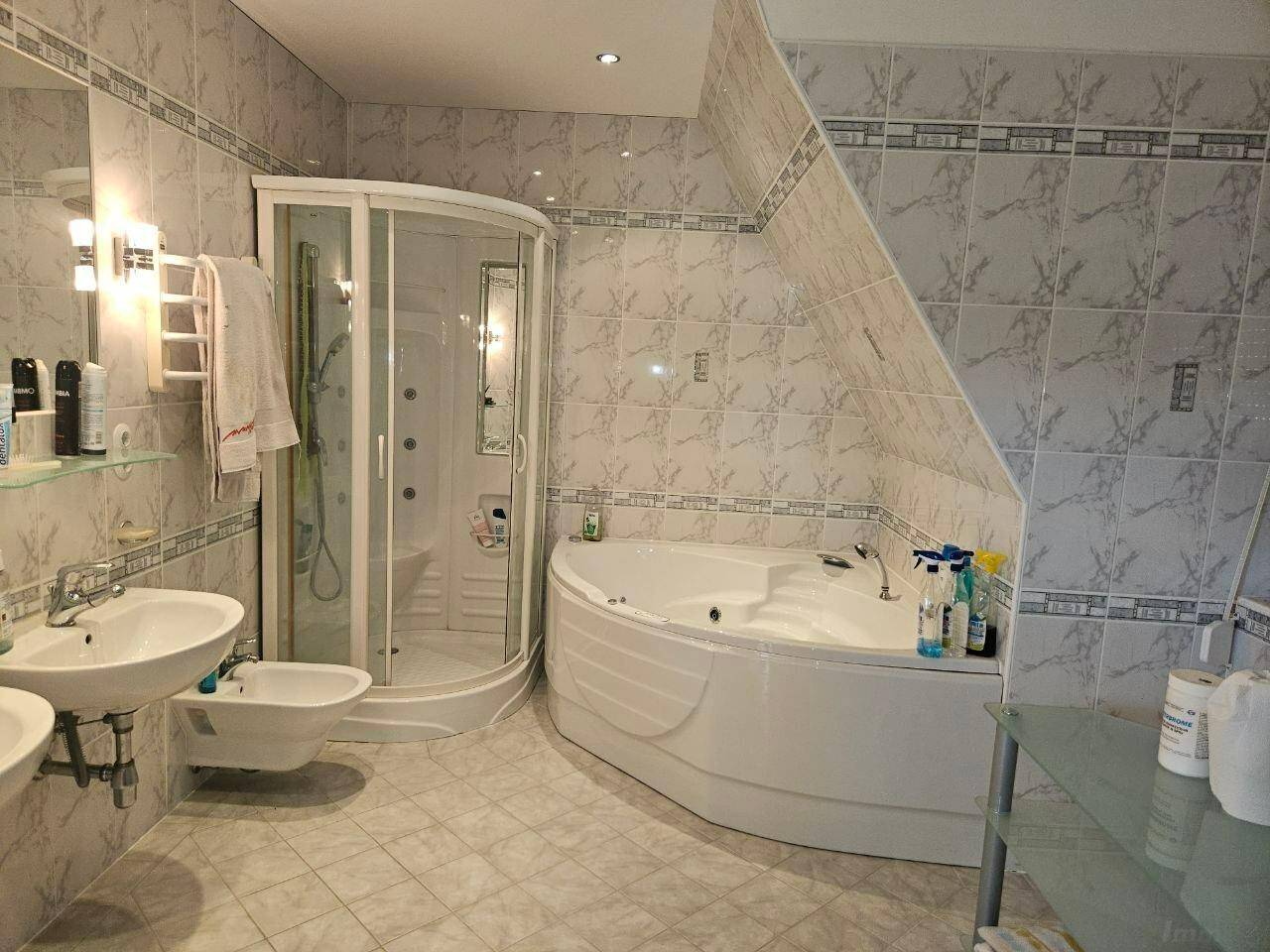 Geräumiges Badezimmer mit Eckbadewanne, Duschkabine, Doppelwaschbecken und Dachschräge.
