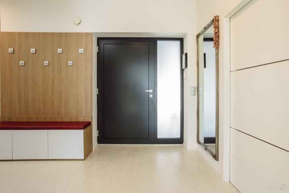 Moderner Eingangsbereich mit Garderobe, Sitzbank und großem Spiegel neben der Haustür.