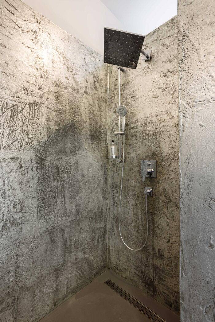 Moderne Duschkabine mit Regendusche und strukturierten grauen Wänden im Industriedesign.