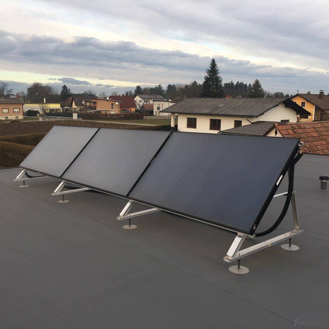 Photovoltaikanlage auf einem Flachdach mit Blick auf die umliegende Wohnsiedlung.