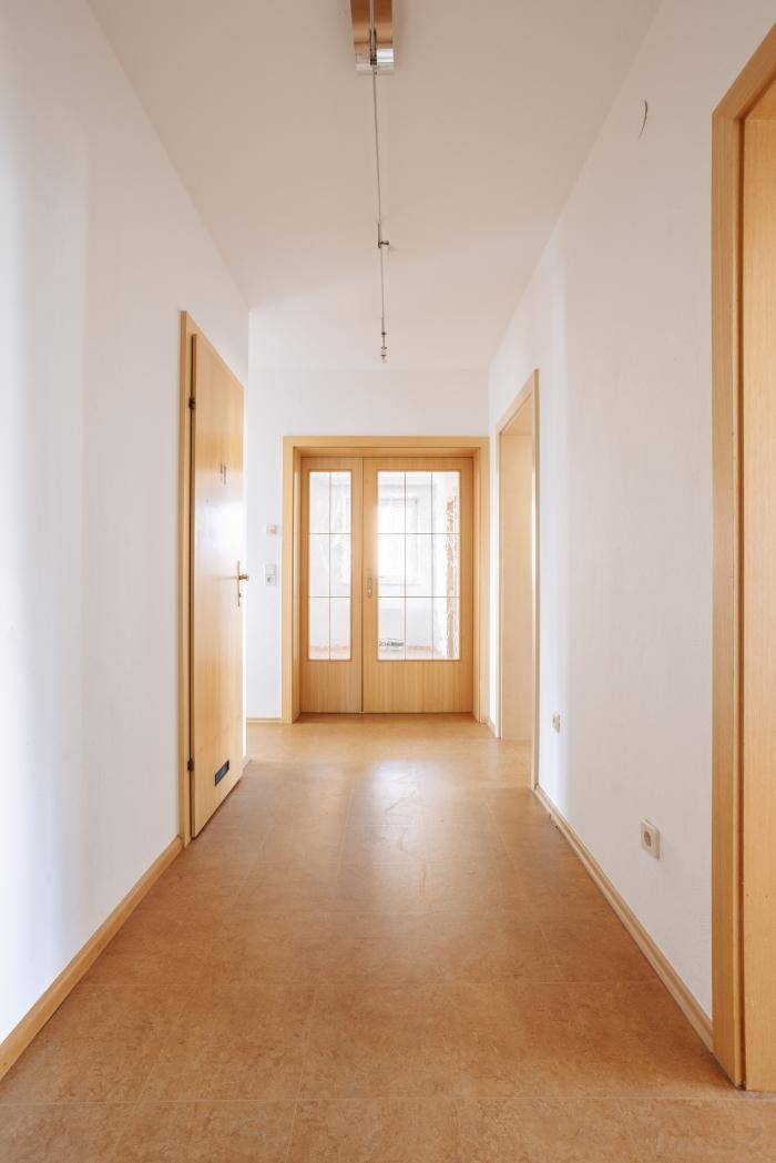 Heller Flur mit Holztüren und Korkboden, der zu weiteren Räumen führt und gut gepflegt ist.