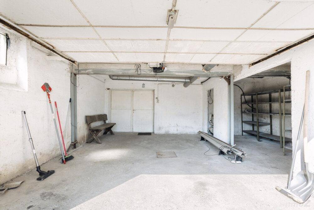 Geräumige Garage mit Betonboden, Stauraum und Zugang zu weiteren Bereichen.
