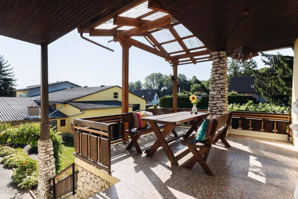 Überdachte Terrasse mit Holztisch und Bänken, ideal für Mahlzeiten im Freien.