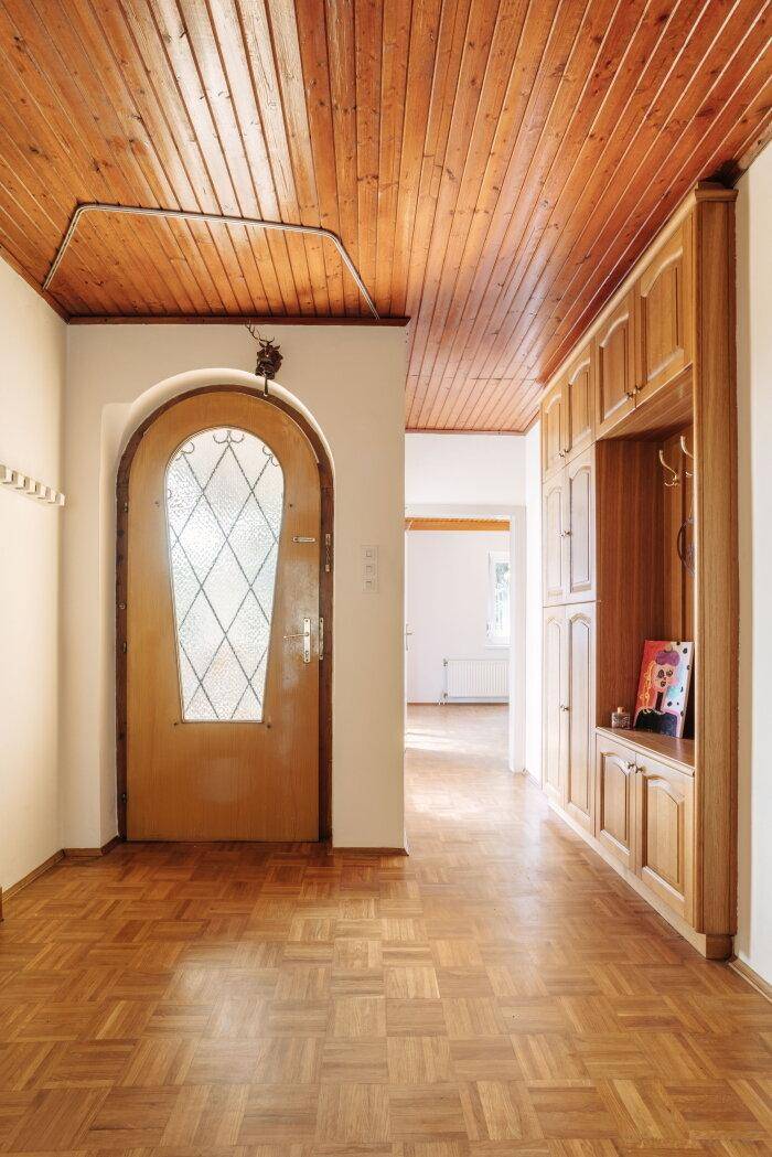 Eingangsbereich mit Holzbalkendecke, Parkettboden und Einbauschränken im Landhausstil.