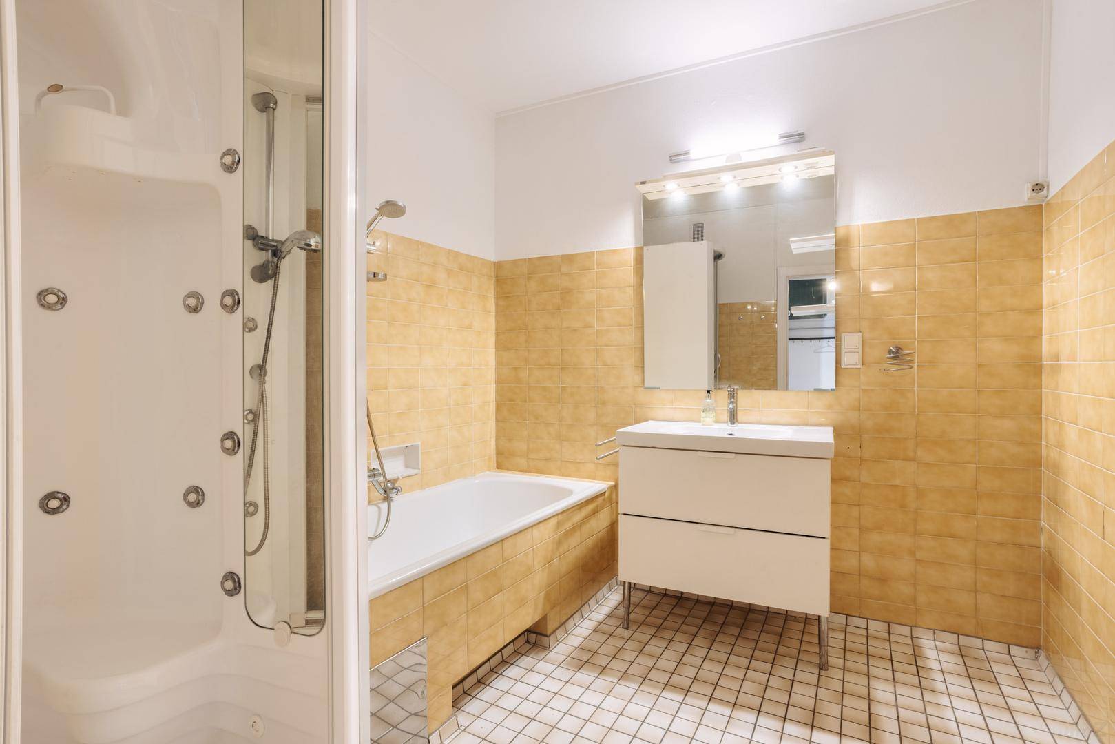 Badezimmer mit gelben Fliesen, Badewanne, Duschkabine und Einzelwaschbecken.
