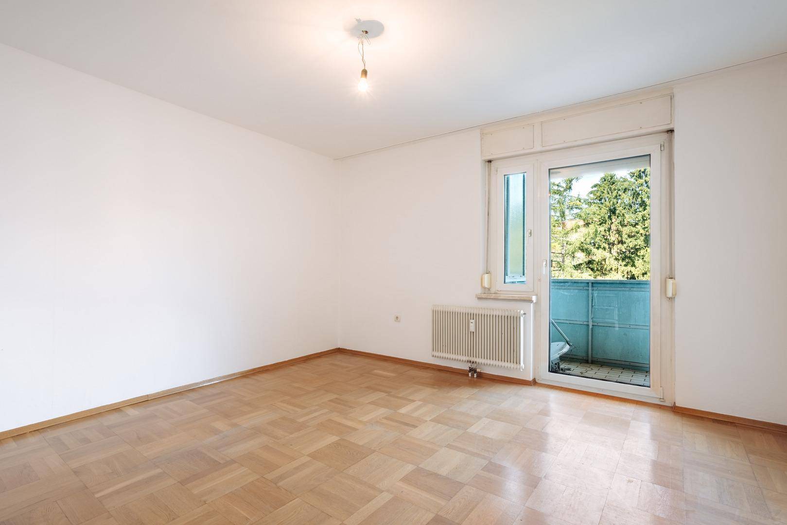 Helles Zimmer mit Parkettboden und Balkontür, ideal als Schlaf- oder Arbeitszimmer.