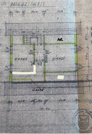 Grundriss des Erdgeschosses mit Zimmern und Treppenhaus, auf blauem Papier.