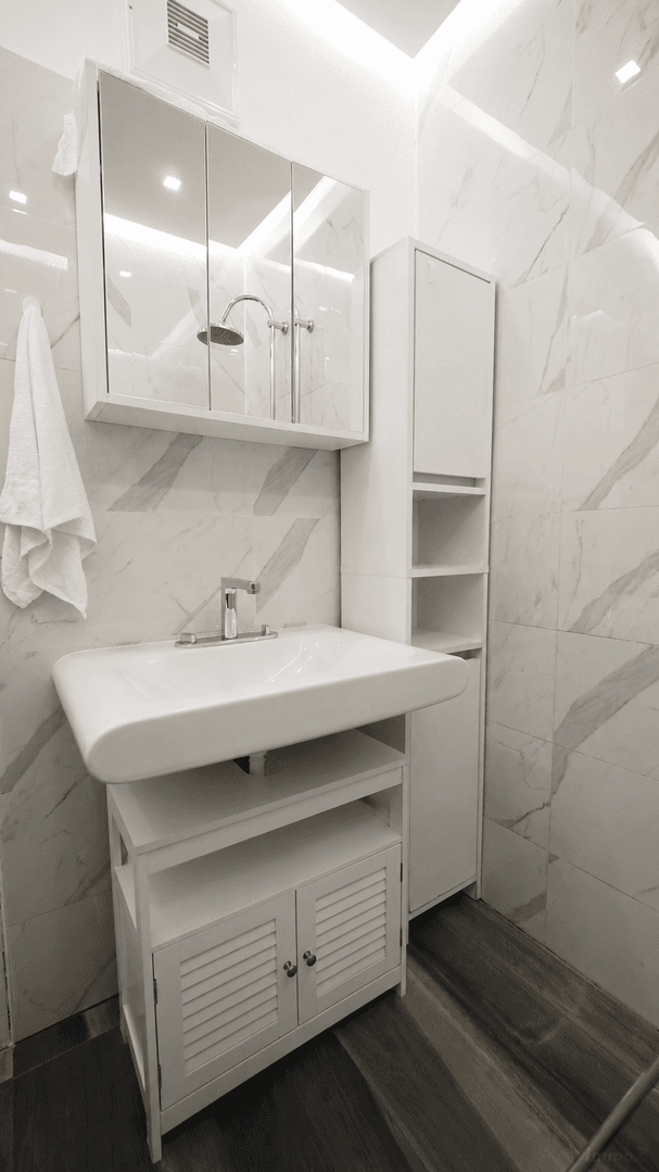 Modernes Badezimmer mit Marmorfliesen, Einzelwaschbecken und Spiegelschrank.