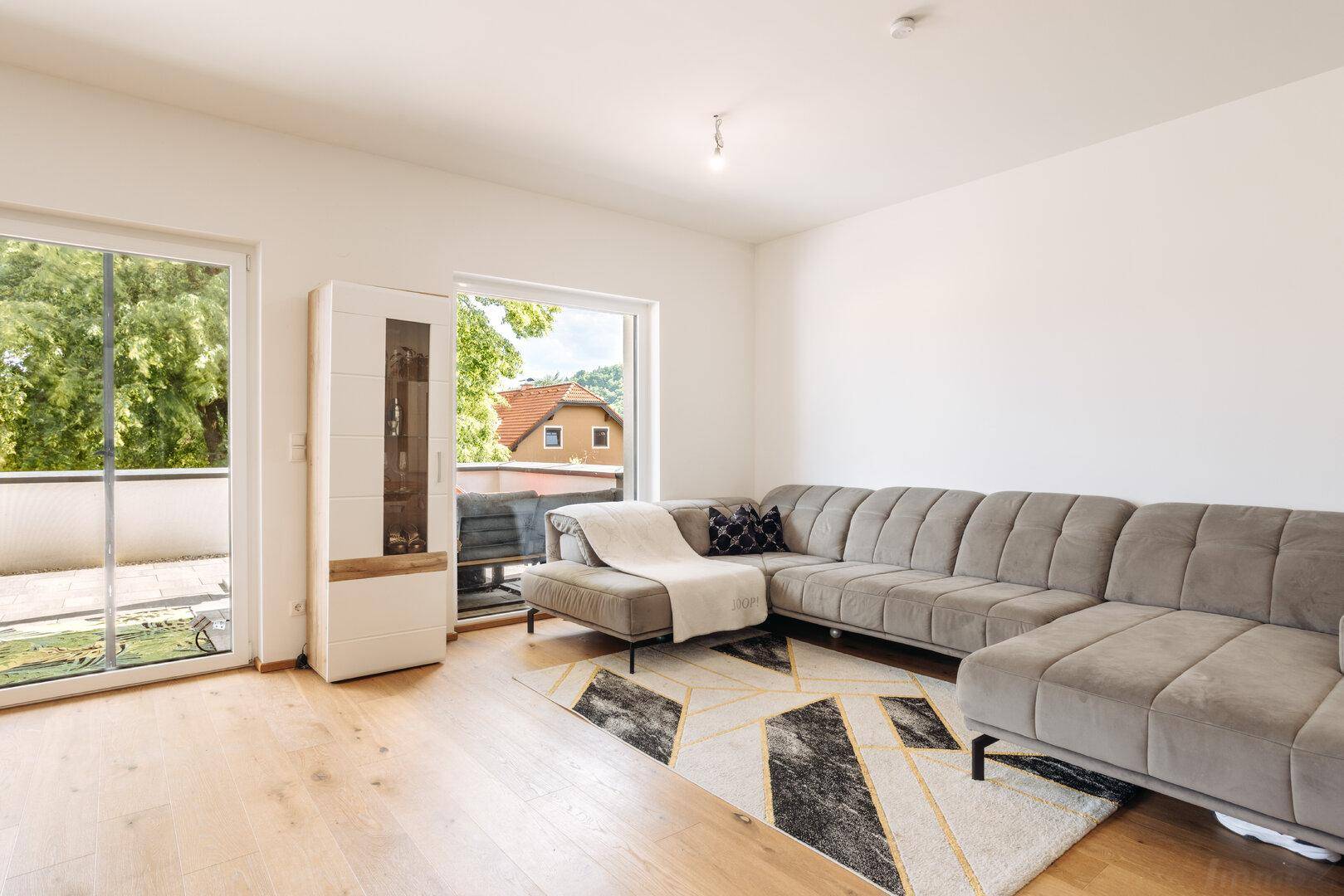 Gemütliches Wohnzimmer mit großem Ecksofa, Holzboden und direktem Zugang zur Terrasse.