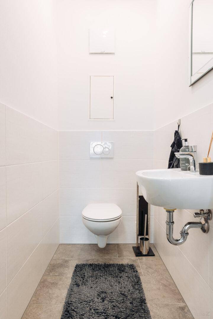 Separates Gäste-WC mit wandhängender Toilette und kleinem Waschbecken.