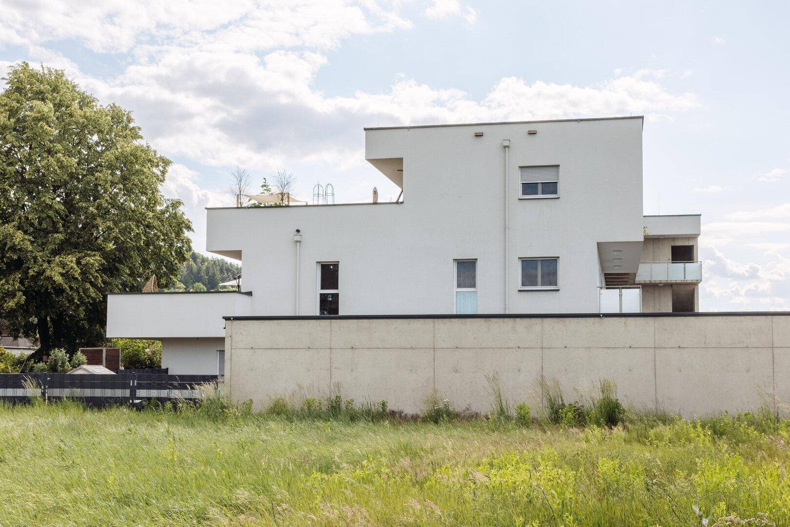 Seitenansicht des modernen Gebäudes mit schlichter Fassade und angrenzender Grünfläche.