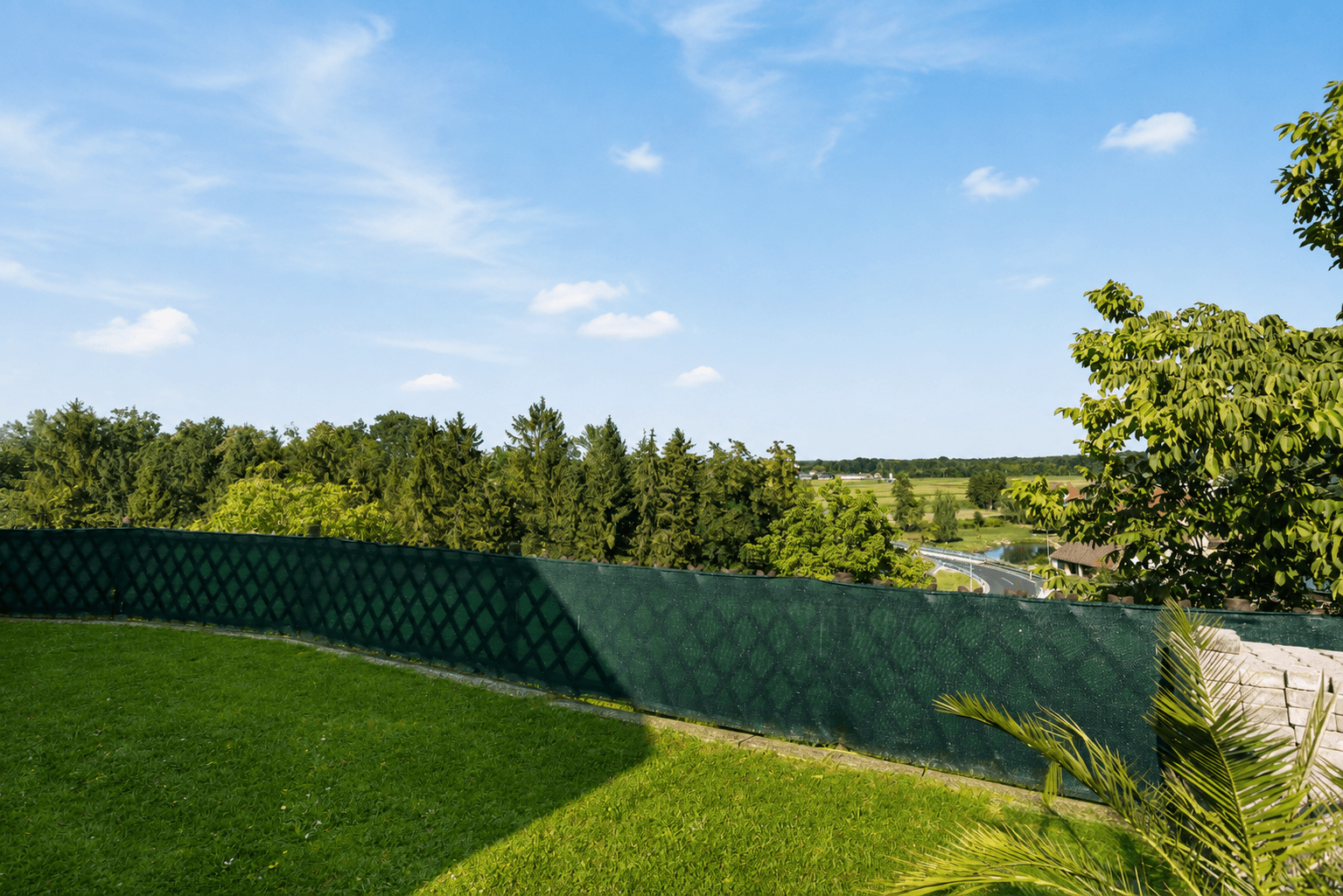 Grüner Gartenbereich mit Rasenfläche und weitem Blick über die umliegende Landschaft.