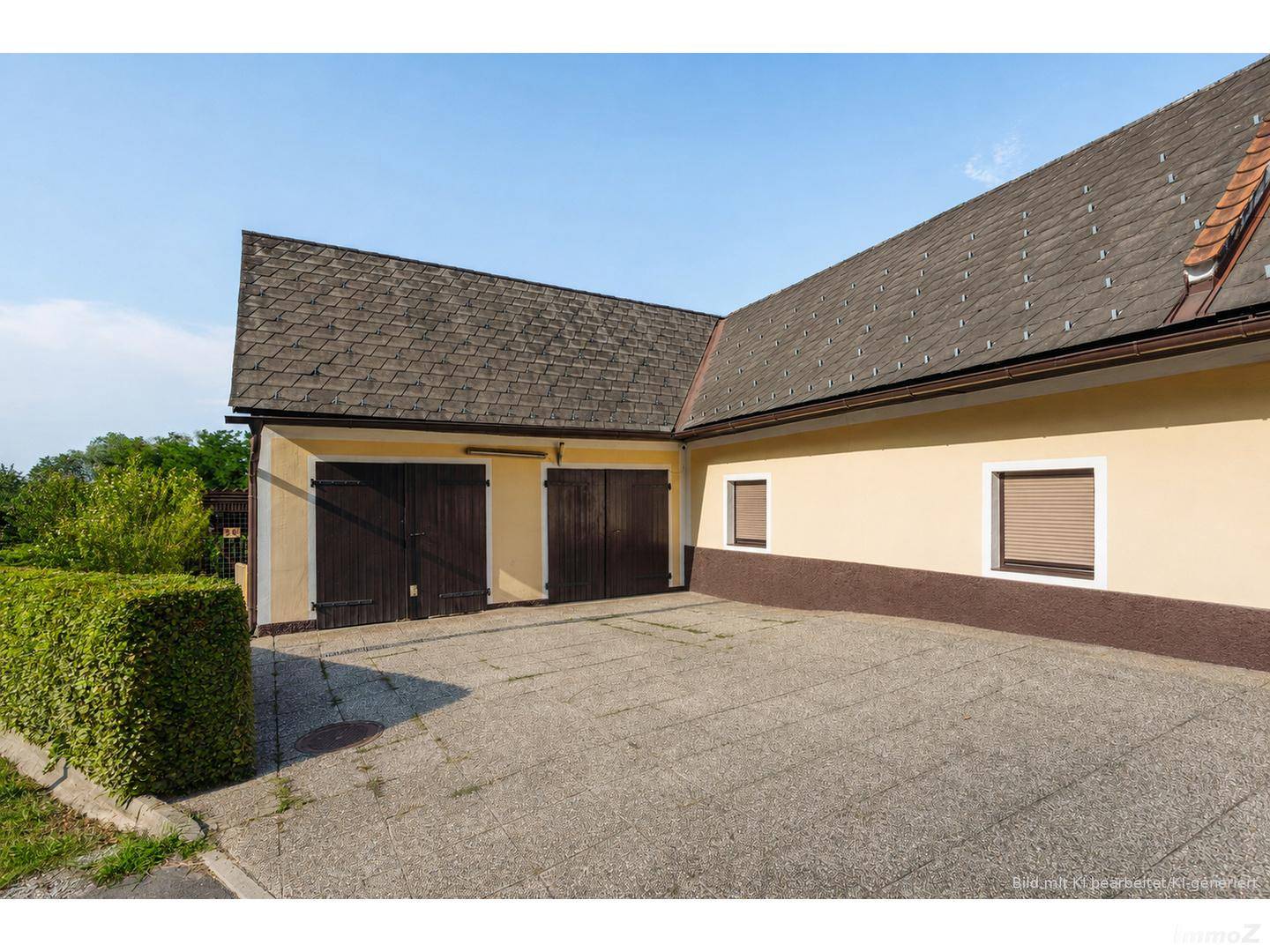 Doppelgarage mit Holztoren und gepflasterter Zufahrt zum Anwesen.